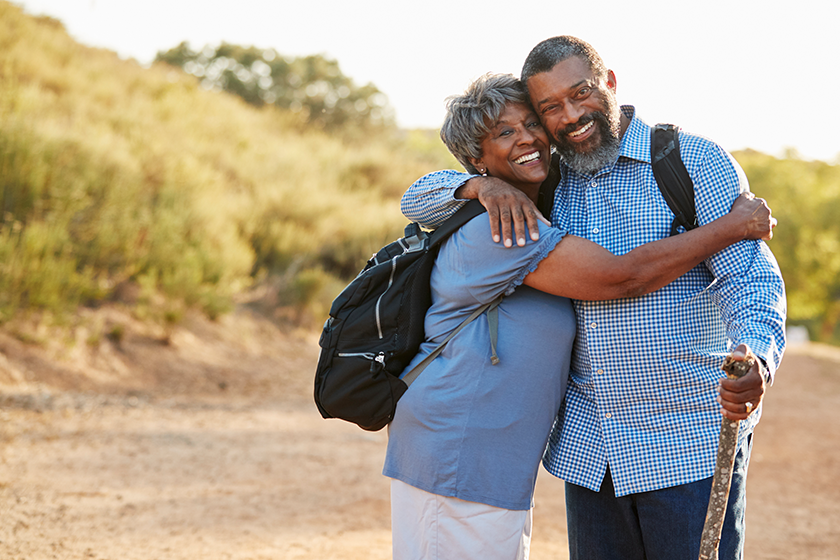 Senior couple wearing backpacks hiking countryside together
