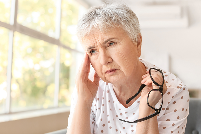 Stressed senior woman suffering headache home