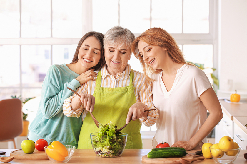 Mature woman with her adult daughter and mother cooking together at home