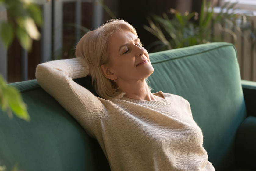 Exhausted mature woman relax on couch with eyes closed