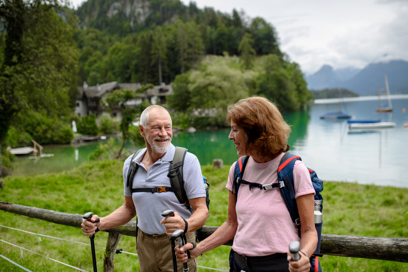 Portrait of active elderly couple hiking together in autumn mountains. Senior tourists looking at lake Portrait of active elderly couple hiking together in autumn mountains. Senior tourists looking at lake