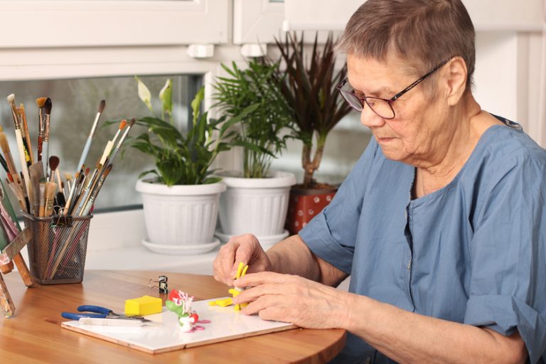 Active old age. An elderly woman sculpts small toys from polymer clay. Art therapy. the age of 80 years. A happy elderly person is engaged in creativity