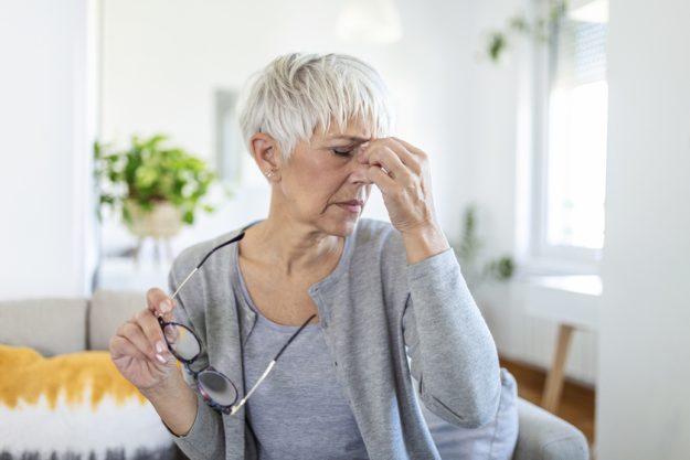 Senior woman in glasses rubs her eyes, suffering from tired eyes, ocular diseases concept Senior woman in glasses rubs her eyes, suffering from tired eyes, ocular diseases concept