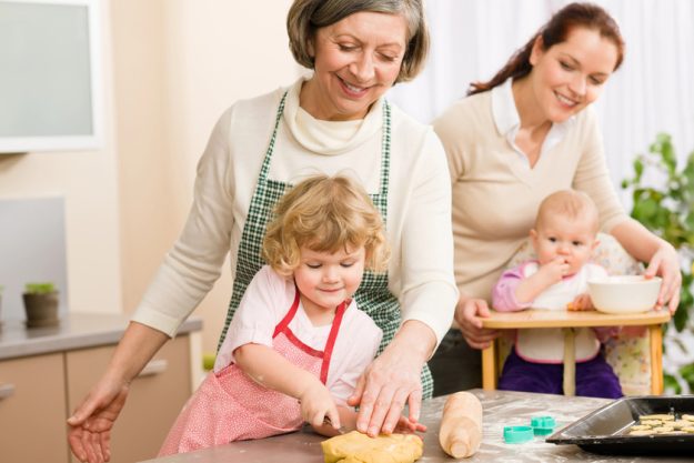Grandmother with little girl prepare dough for baking in kitchen Grandmother with little girl prepare dough for baking in kitchen