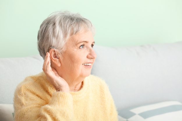 Senior woman with hearing aid at home