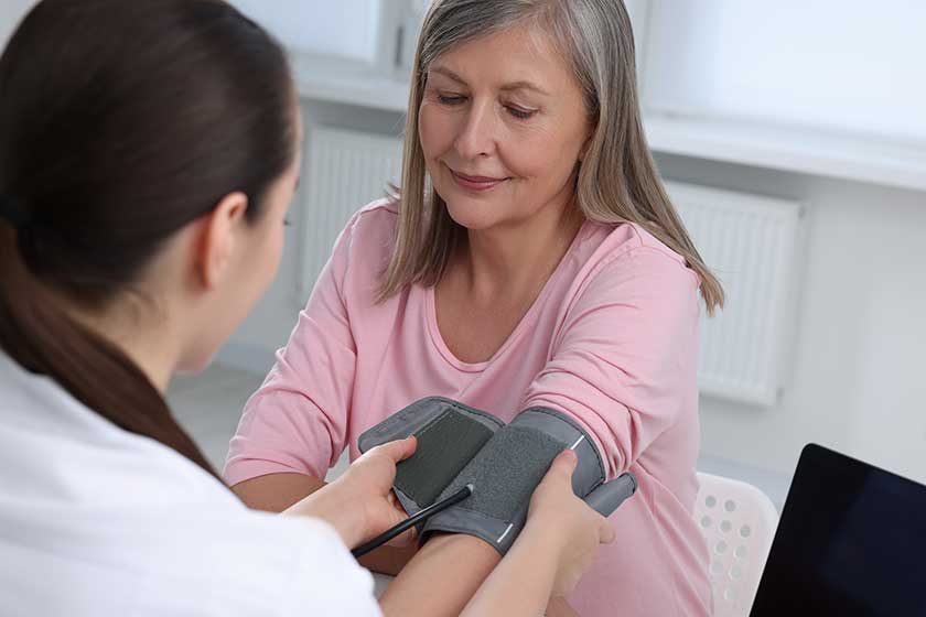 Doctor measuring blood pressure woman table indoors