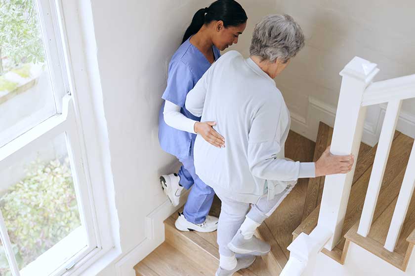 Nurse senior woman support stairs help walk nursing home caregiver