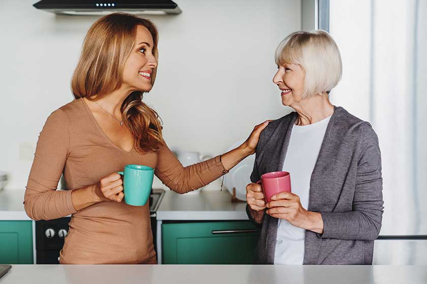 Senior woman enjoying meeeting her daughter kitchen drinking tea coffee