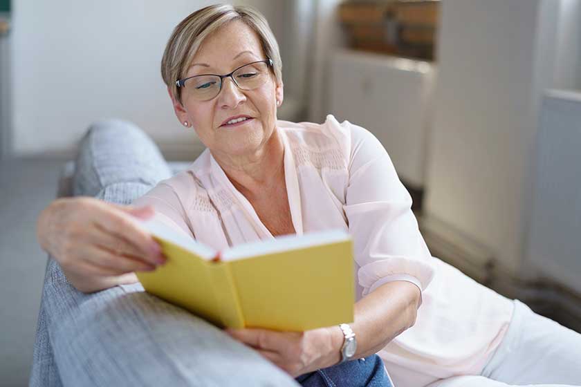 Senior woman reading book on sofa Senior woman reading book on sofa
