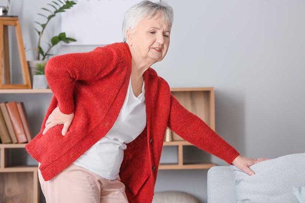 Senior woman suffering from back pain at home