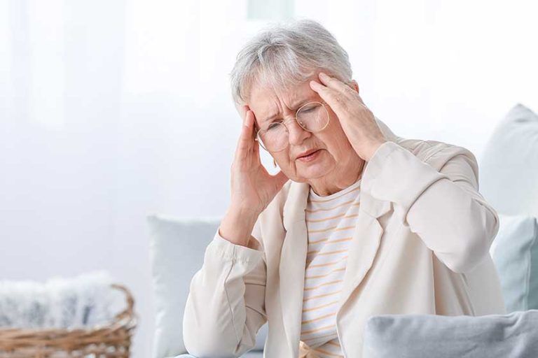 Senior woman suffering from headache at home