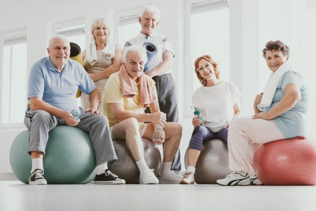 Group,Of,Active,Seniors,Sitting,On,Exercising,Balls,In,Modern