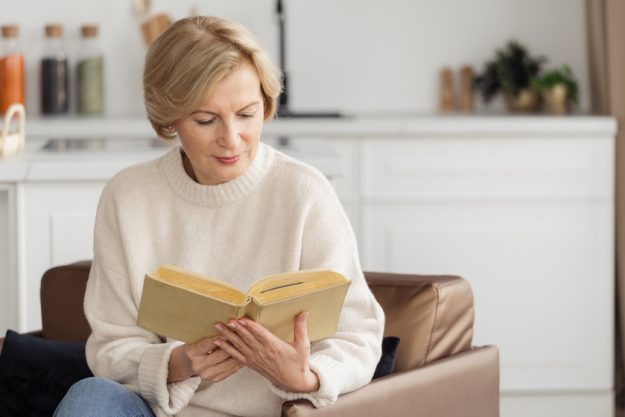 Mature woman reading book while she resting at home