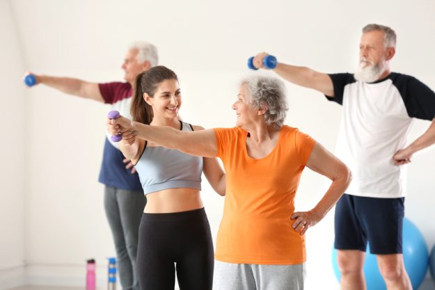 Elderly people training with instructor in gym