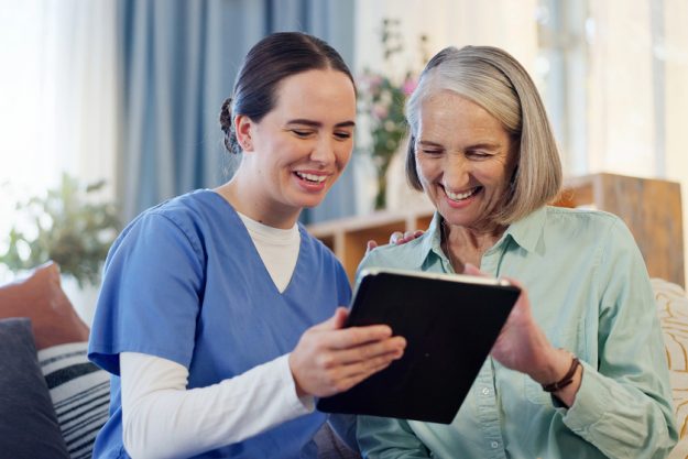 Happy, caregiver and technology in living room for retirement, internet or online app for medical support.