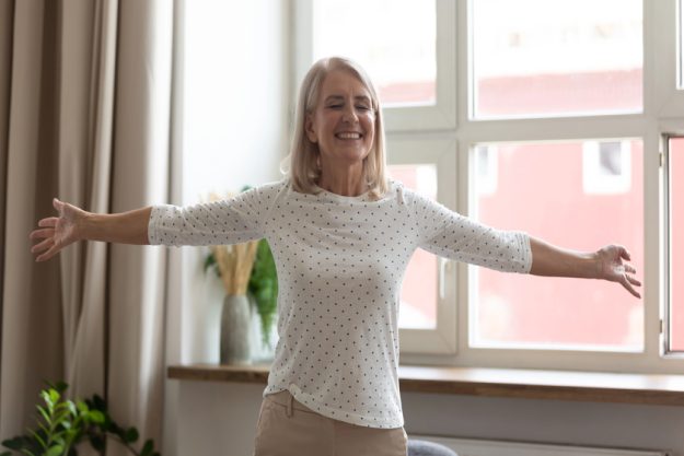 Happy mature woman standing with arms outstretched, enjoying life Happy mature woman standing with arms outstretched, enjoying life