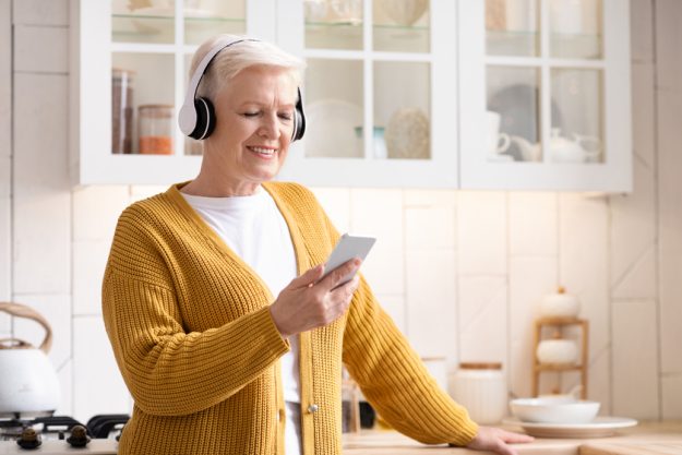 Happy senior woman listening to music on smartphone at home Happy senior woman listening to music on smartphone at home