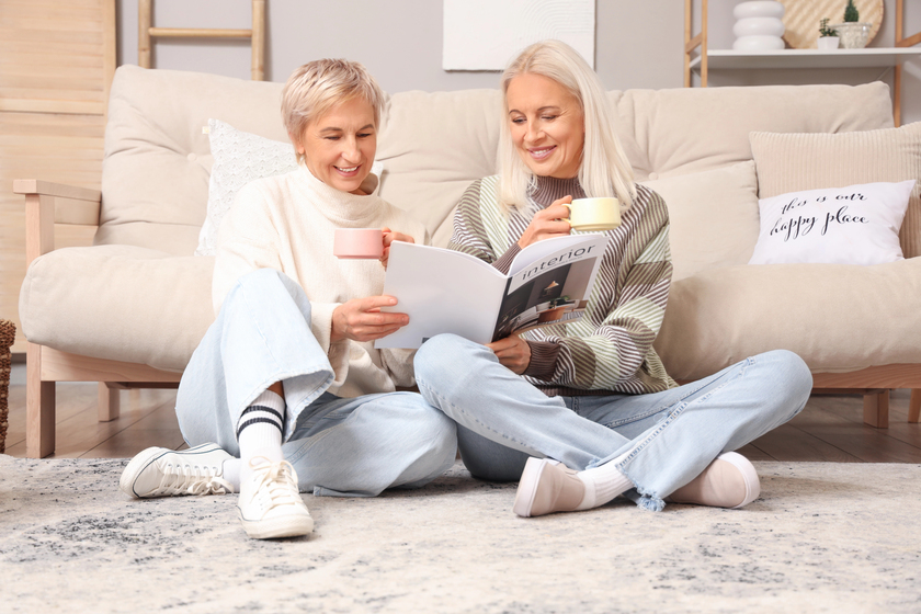 Mature women with cups of tea reading magazine at home Mature women with cups of tea reading magazine at home