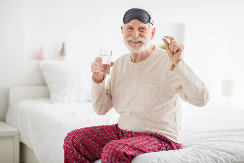 Photo of pretty attractive age pensioner sleepwear sitting bed drinking water medicine inside indoors home room