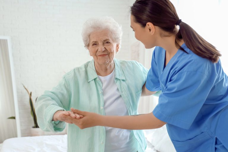 Physical therapist helping senior woman in bedroom Physical therapist helping senior woman in bedroom