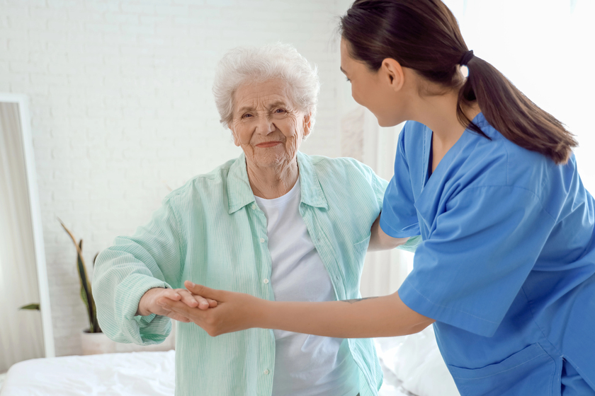 Physical therapist helping senior woman in bedroom Physical therapist helping senior woman in bedroom