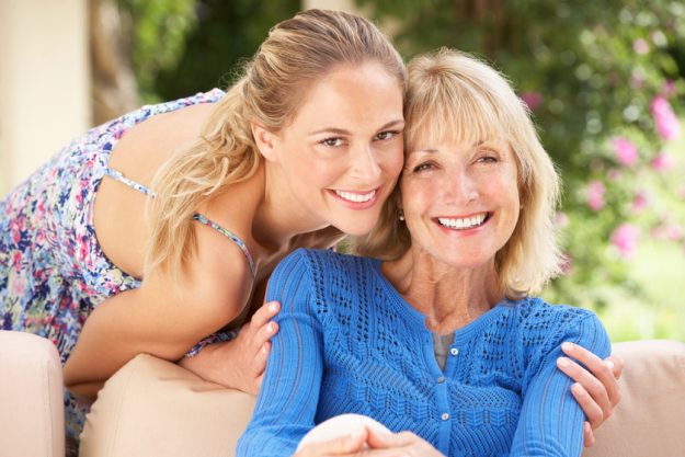 Senior Woman With Adult Daughter Relaxing On Sofa At Home