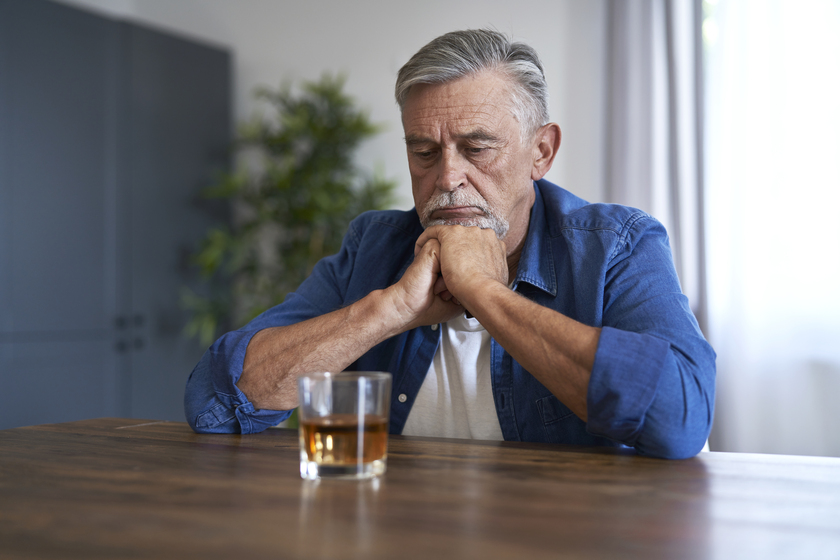 Senior caucasian man sitting and looking at the glass with whiskey at home Senior caucasian man sitting and looking at the glass with whiskey at home