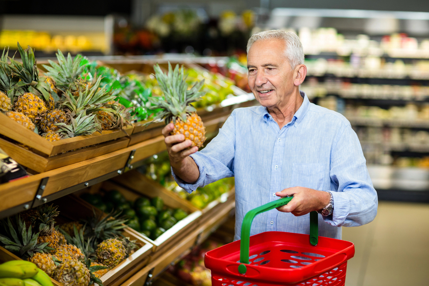 Smiling senior man picking pineapple in supermarket Smiling senior man picking pineapple in supermarket