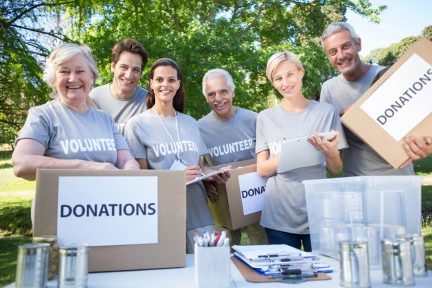Happy volunteer family holding donation boxes on a sunny day