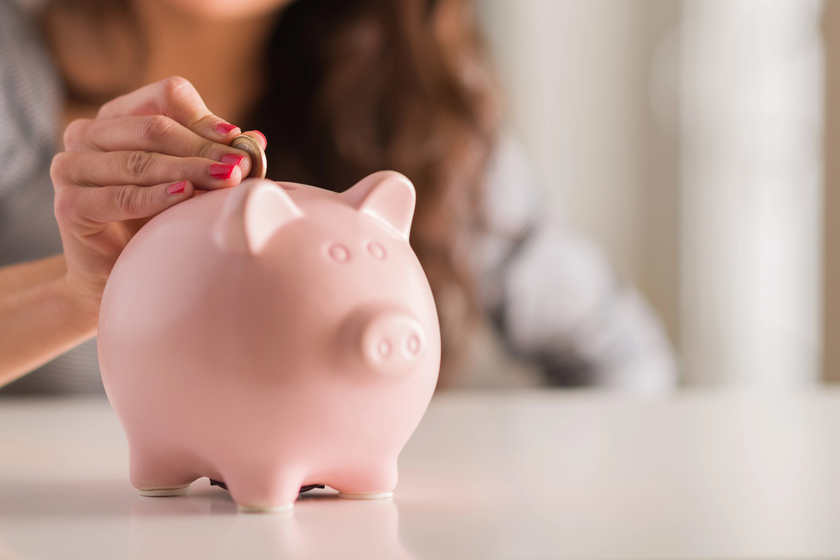 Woman Putting Coin In Piggy Bank Woman Putting Coin In Piggy Bank
