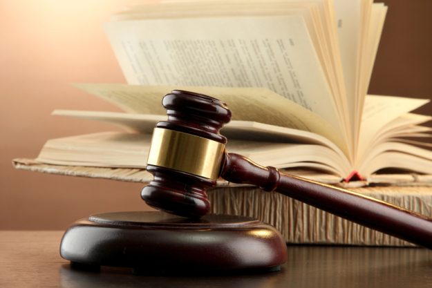 Wooden gavel and books on wooden table,on brown background Wooden gavel and books on wooden table,on brown background
