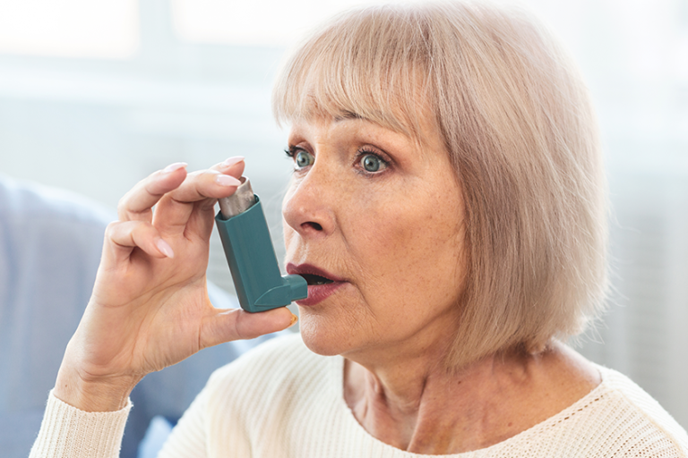 Elderly woman using asthma inhaler for allergies Elderly woman using asthma inhaler for allergies