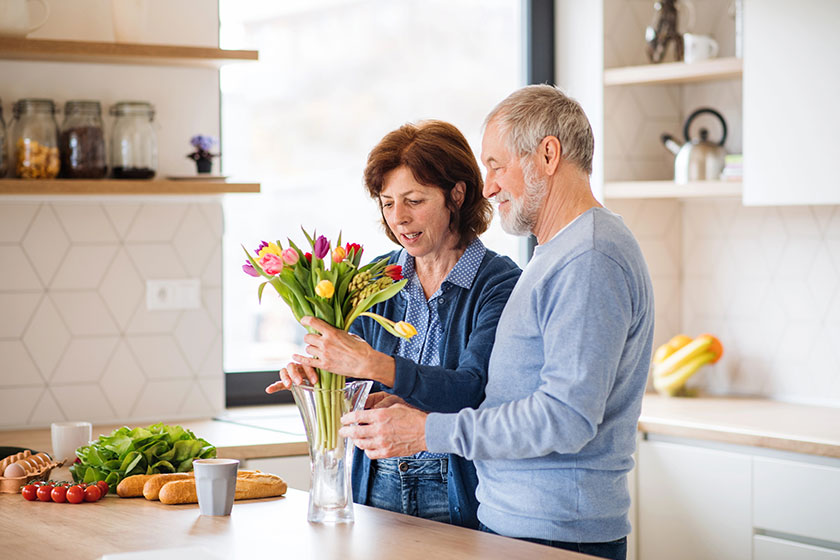 A portrait of senior couple in love indoors at home unpacking shopping