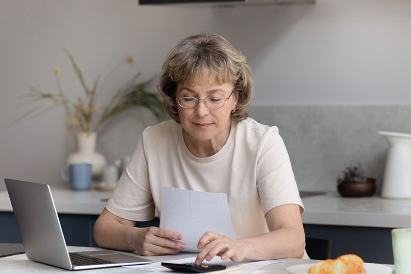 Focused middle aged woman calculating bills at home Focused middle aged woman calculating bills at home
