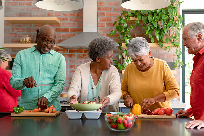 Group happy diverse senior male female friends cooking together home