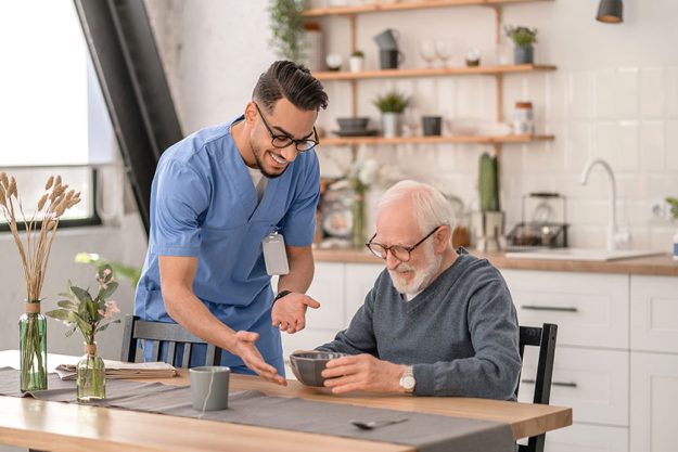 Joyous amiable volunteer serving the meal to an aged man