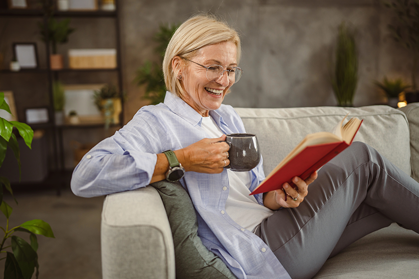 mature woman sit living room read book drink coffee