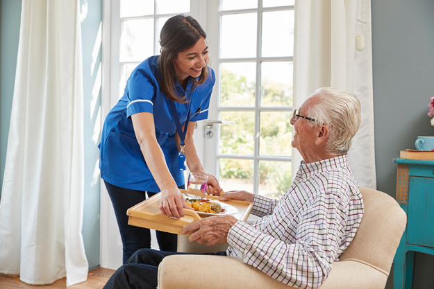 nurse serving dinner to a senior man nurse serving dinner to a senior man