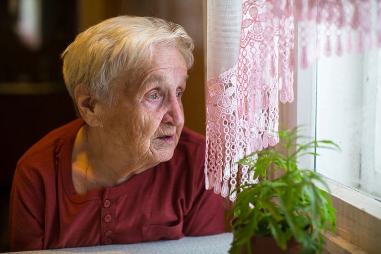 Older woman longing looks out window