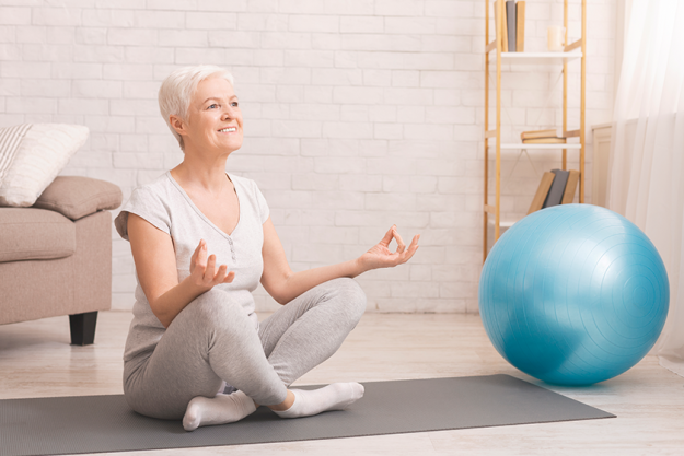 peaceful senior woman meditating on floor peaceful senior woman meditating on floor