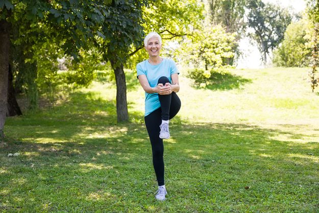 Portrait senior woman doing streching exercise park