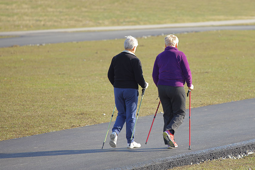 Scandinavian nordic walking two older women are engaged in sports even down the paved path