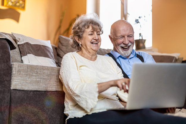 Senior couple using laptop home