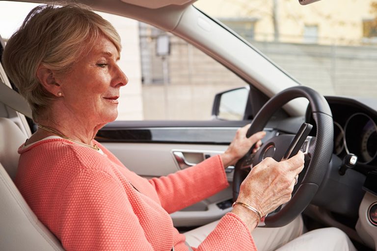 Senior female driver using smartphone