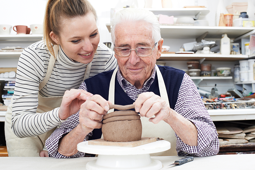 senior man with teacher in pottery class senior man with teacher in pottery class