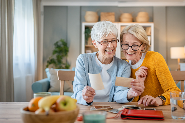 senior mature women friends sisters looking family photos album