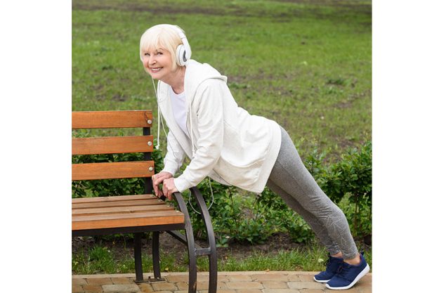 Senior sportswoman headphones doing push bench park Senior sportswoman headphones doing push bench park