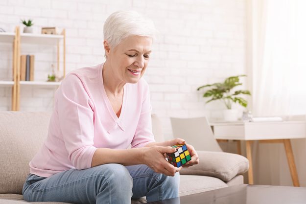 Senior woman playing with rubiks cube during quarantineg Senior woman playing with rubiks cube during quarantineg