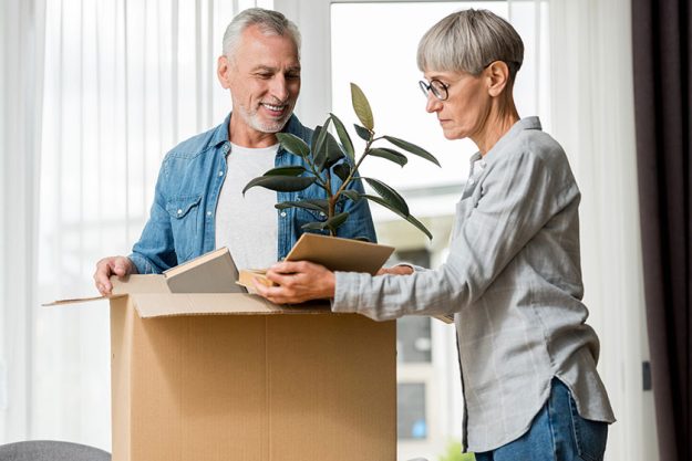 Smiling man mature woman unpacking box new house