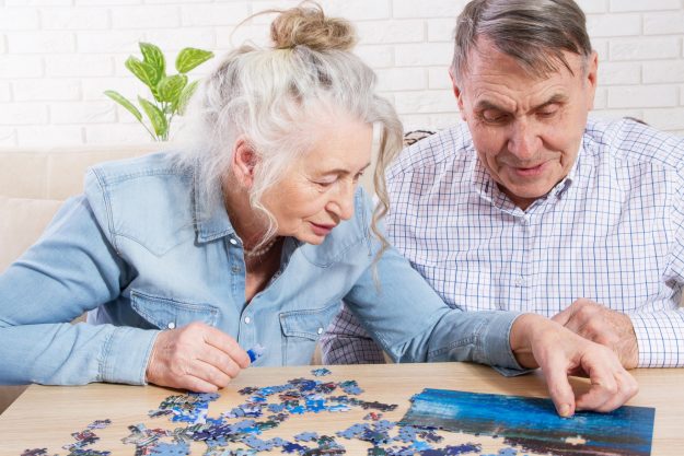 Senior couple solving jigsaw puzzle together at home Senior couple solving jigsaw puzzle together at home